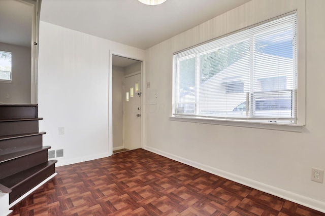 unfurnished room featuring dark parquet floors and a healthy amount of sunlight