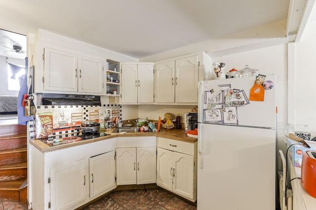 kitchen featuring backsplash, sink, black stovetop, and white refrigerator