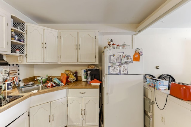 kitchen with white cabinets, cooktop, white fridge, and sink