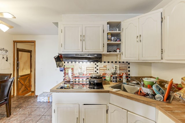 kitchen with black electric cooktop, sink, light tile patterned floors, white cabinets, and range hood