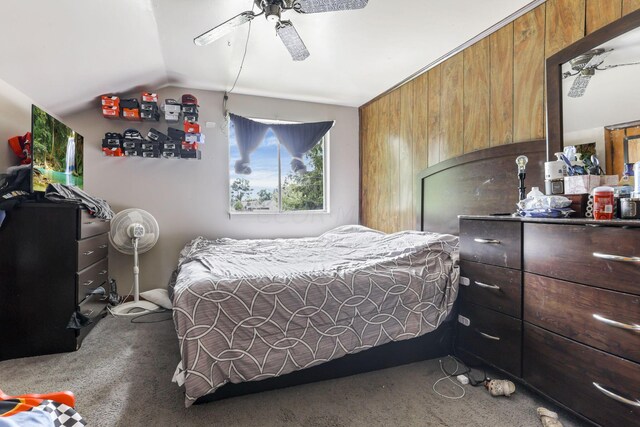 carpeted bedroom featuring ceiling fan, wooden walls, and lofted ceiling