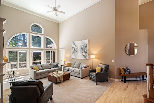 living room featuring ceiling fan, light hardwood / wood-style flooring, a high ceiling, and ornamental molding