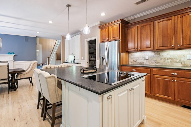 kitchen with stainless steel refrigerator with ice dispenser, black electric cooktop, crown molding, light hardwood / wood-style floors, and hanging light fixtures