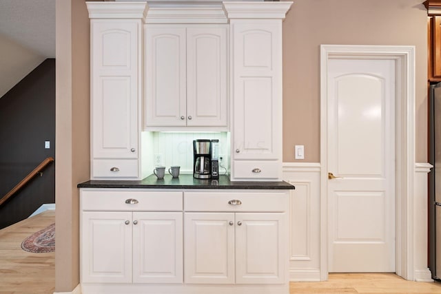 bar featuring white cabinets, a textured ceiling, light hardwood / wood-style flooring, and lofted ceiling