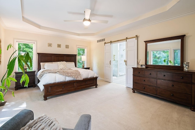 carpeted bedroom with a tray ceiling, ceiling fan, crown molding, and ensuite bathroom