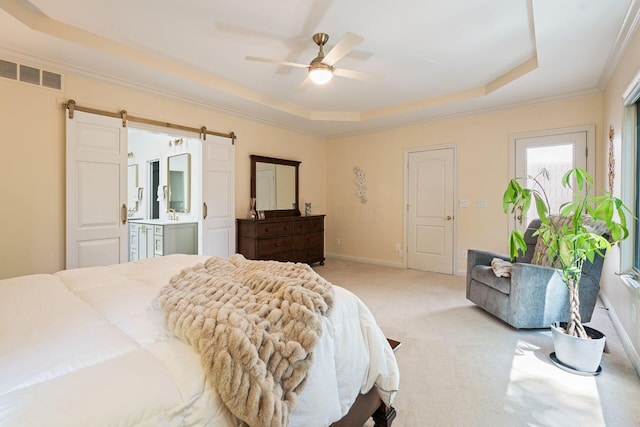 bedroom featuring ensuite bath, a tray ceiling, light colored carpet, ceiling fan, and a barn door