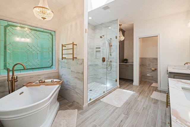 bathroom with vanity, separate shower and tub, tile walls, and a notable chandelier