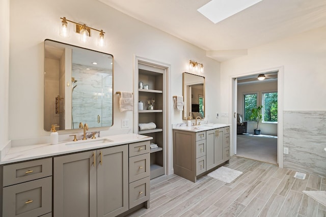 bathroom featuring hardwood / wood-style flooring, vanity, a shower with shower door, and a skylight