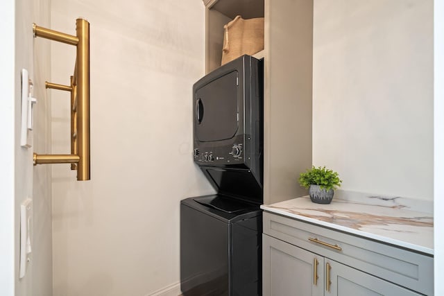 laundry room featuring stacked washer and dryer and cabinets