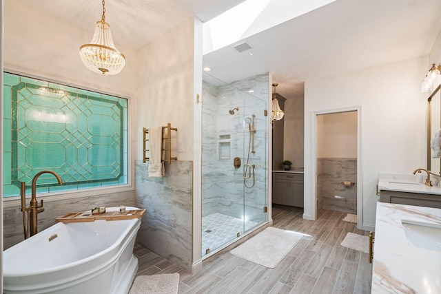 bathroom featuring vanity, shower with separate bathtub, tile walls, and an inviting chandelier