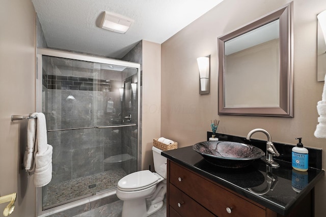 bathroom featuring vanity, an enclosed shower, a textured ceiling, and toilet