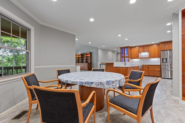 dining space with crown molding and sink