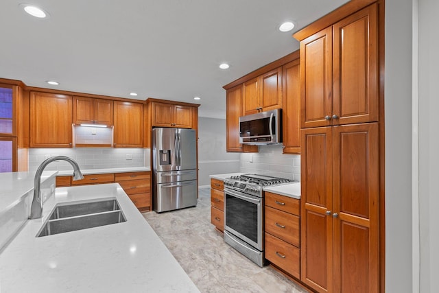 kitchen with decorative backsplash, light stone countertops, sink, and appliances with stainless steel finishes