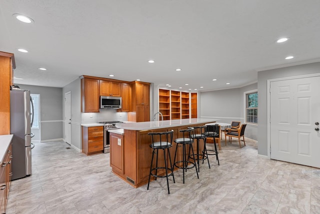 kitchen featuring a kitchen bar, appliances with stainless steel finishes, decorative backsplash, sink, and a kitchen island