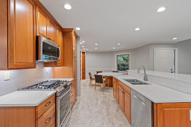 kitchen featuring backsplash, a kitchen island with sink, sink, light wood-type flooring, and stainless steel appliances