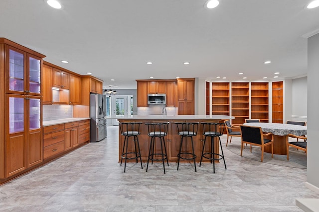 kitchen with a center island with sink, a breakfast bar, backsplash, and appliances with stainless steel finishes