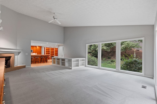 unfurnished living room with light carpet, ceiling fan, and a brick fireplace