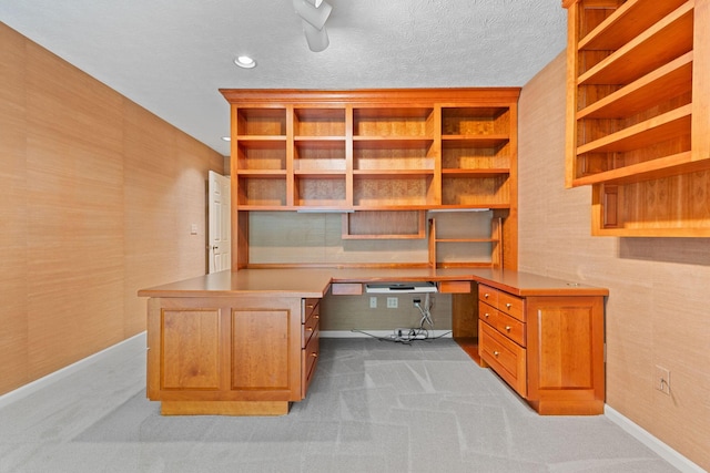 office area featuring light carpet, built in desk, and a textured ceiling