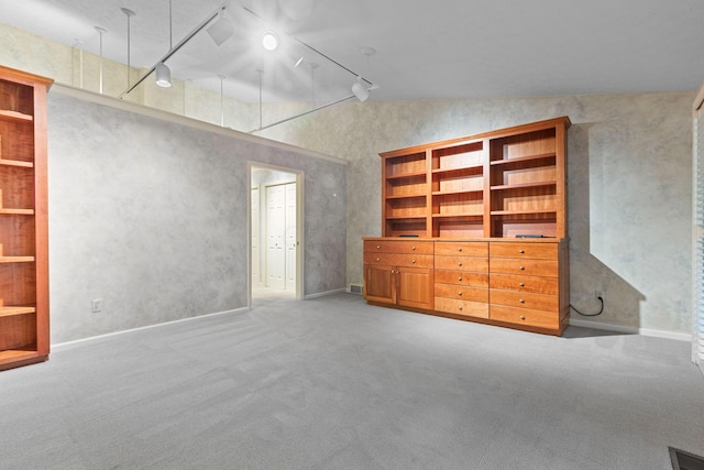 unfurnished living room with carpet, built in shelves, lofted ceiling, and rail lighting