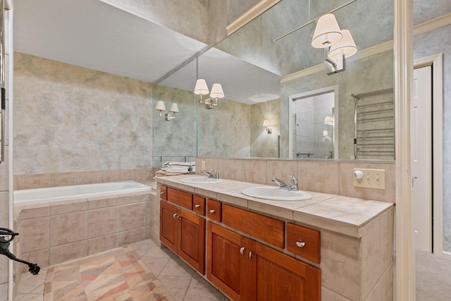 bathroom featuring tile patterned flooring, vanity, ornamental molding, and tiled bath