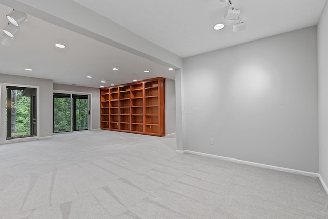 unfurnished room with rail lighting and light colored carpet