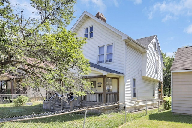 rear view of house featuring covered porch and a yard