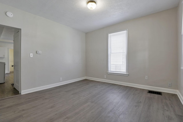 spare room with a textured ceiling and hardwood / wood-style flooring