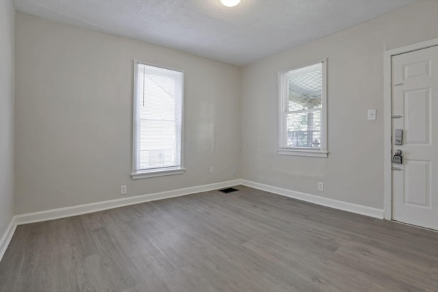 unfurnished room with a textured ceiling and hardwood / wood-style flooring