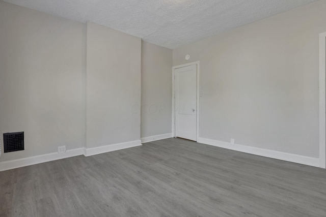 empty room with hardwood / wood-style floors and a textured ceiling