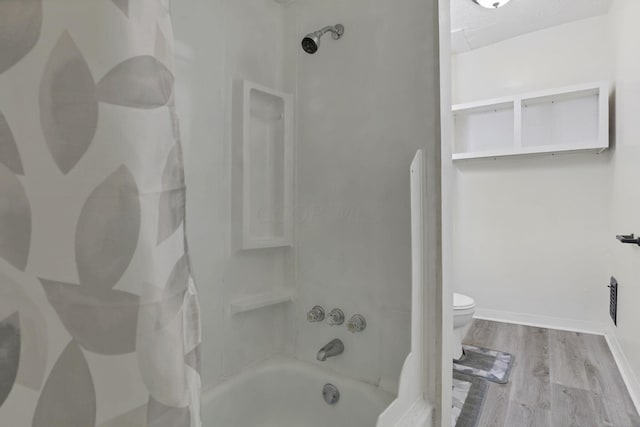 bathroom featuring wood-type flooring, tiled shower / bath combo, and toilet