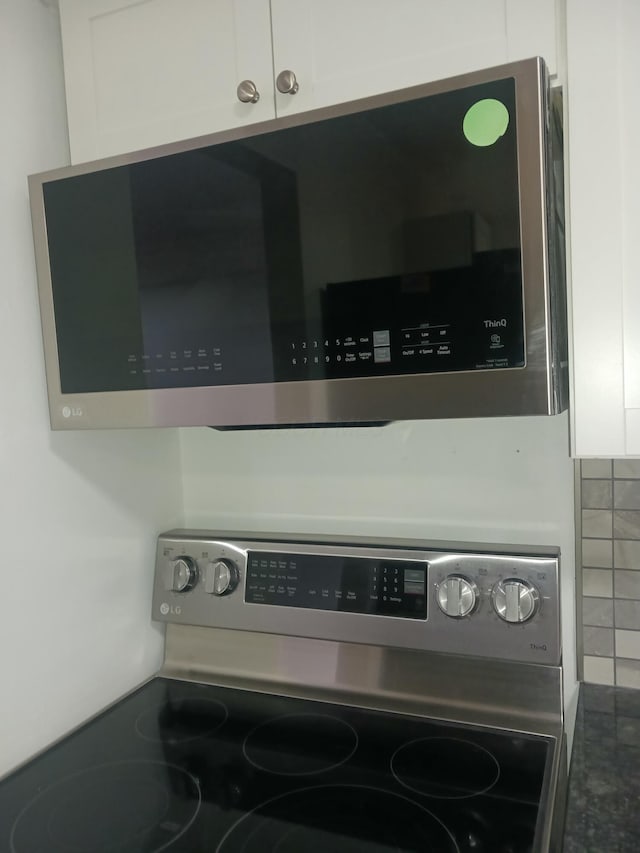 room details featuring backsplash, white cabinets, and stainless steel appliances