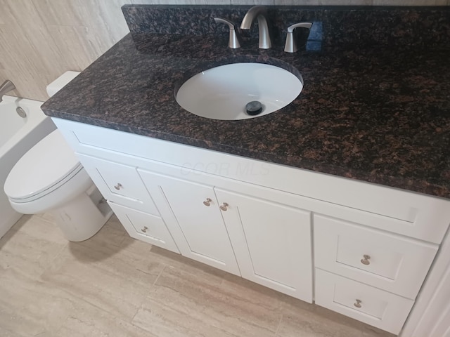 bathroom with backsplash, a tub, vanity, and toilet