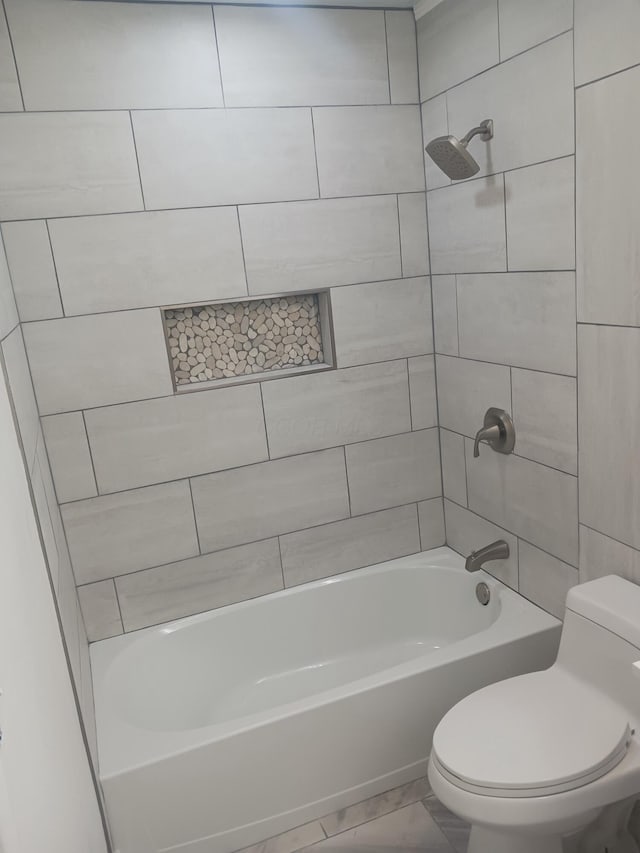 bathroom with tiled shower / bath combo and toilet