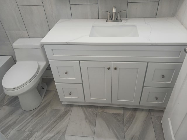 bathroom with vanity, tile walls, and toilet