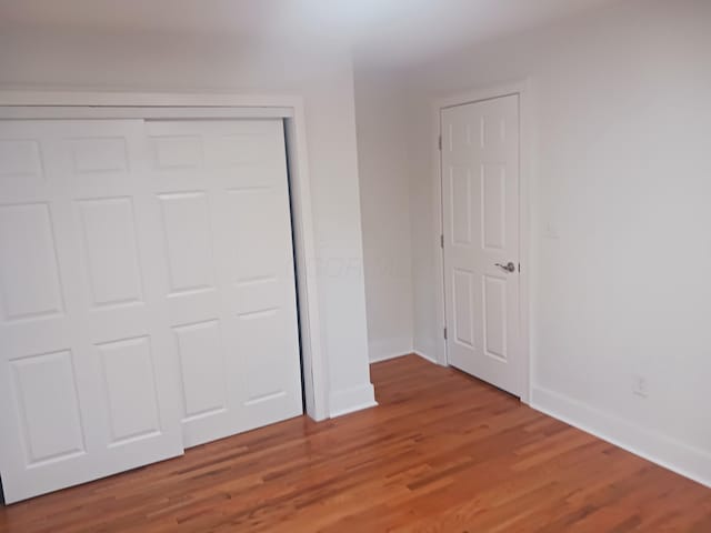 unfurnished bedroom with a closet and hardwood / wood-style flooring