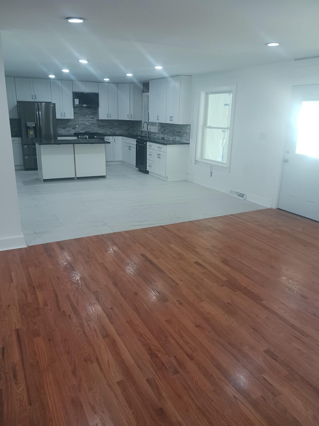 kitchen with a wealth of natural light, light hardwood / wood-style floors, white cabinetry, fridge with ice dispenser, and extractor fan