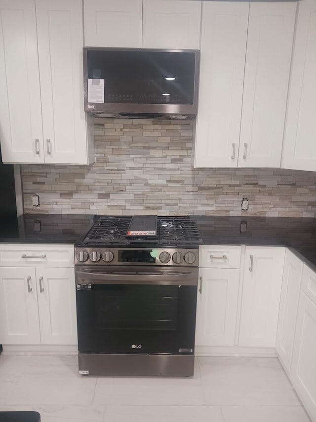 kitchen featuring tasteful backsplash, white cabinetry, range hood, and stainless steel range with gas stovetop