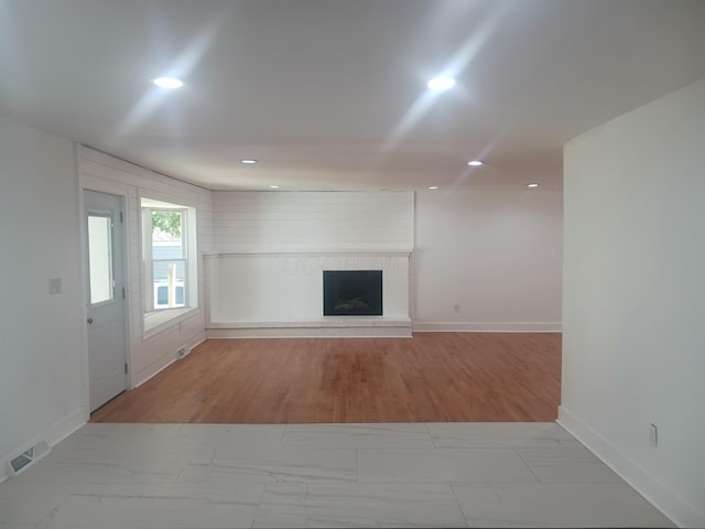 unfurnished living room featuring light wood-type flooring and a brick fireplace