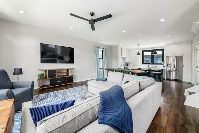 living room featuring dark hardwood / wood-style floors, ceiling fan, and sink