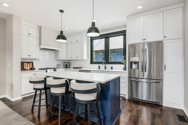 kitchen with dark hardwood / wood-style flooring, stainless steel appliances, decorative light fixtures, white cabinets, and a kitchen island