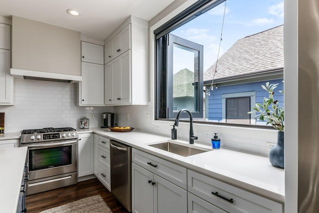 kitchen with white cabinetry, sink, dark hardwood / wood-style floors, backsplash, and appliances with stainless steel finishes