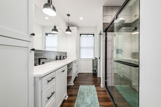 bathroom with wood-type flooring, vanity, tasteful backsplash, and a shower with door