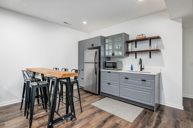 kitchen with stainless steel appliances, gray cabinets, dark wood-type flooring, and sink