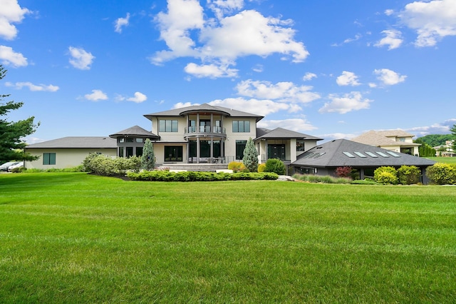 rear view of property with a balcony and a yard