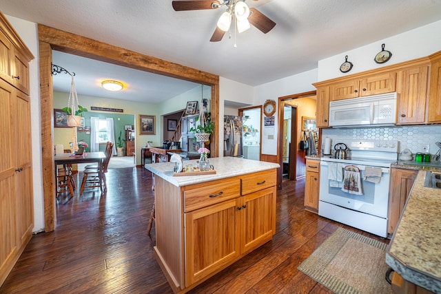 kitchen with white appliances, a kitchen island, ceiling fan, and dark wood-type flooring