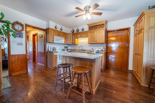 kitchen featuring dark hardwood / wood-style flooring, white appliances, a center island, and wooden walls