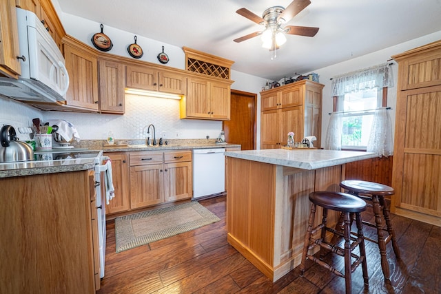 kitchen featuring ceiling fan, sink, dark hardwood / wood-style floors, white appliances, and a kitchen island