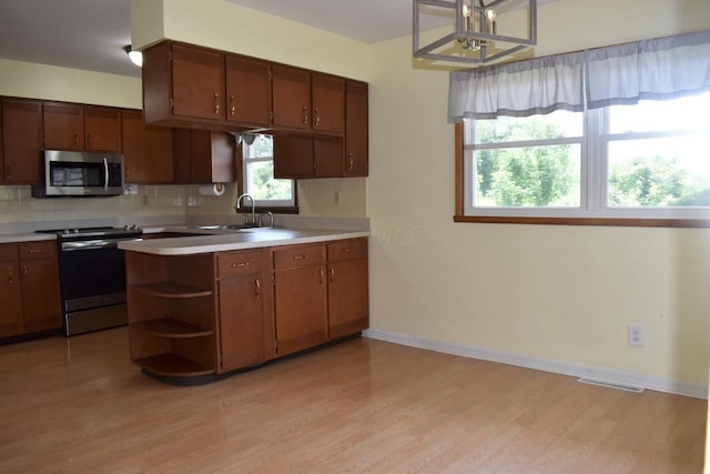 kitchen featuring appliances with stainless steel finishes, light hardwood / wood-style floors, pendant lighting, and sink