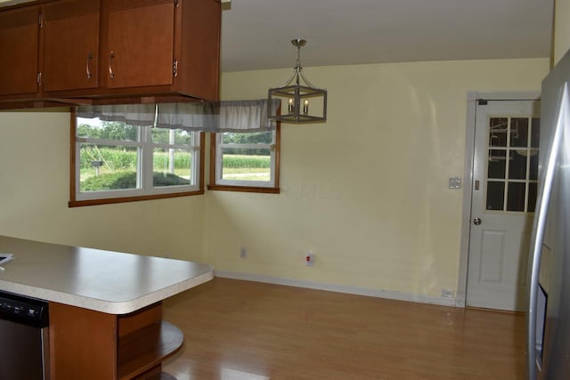 kitchen with an inviting chandelier, stainless steel dishwasher, kitchen peninsula, pendant lighting, and light hardwood / wood-style floors