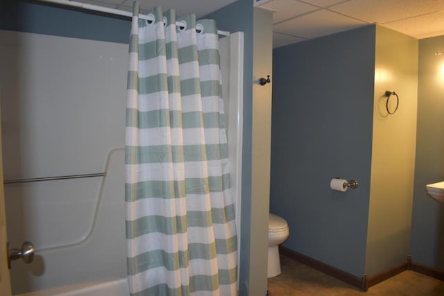 bathroom with shower / bath combination with curtain, toilet, and a drop ceiling